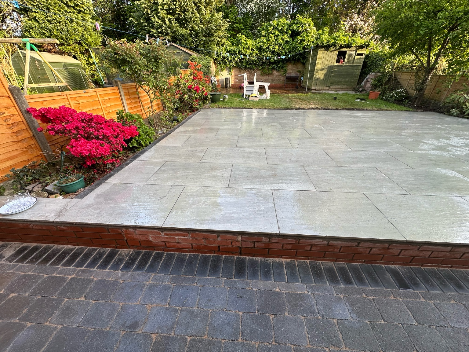 Grey porcelain patio raised on a red brick wall with azaleas, Worcester